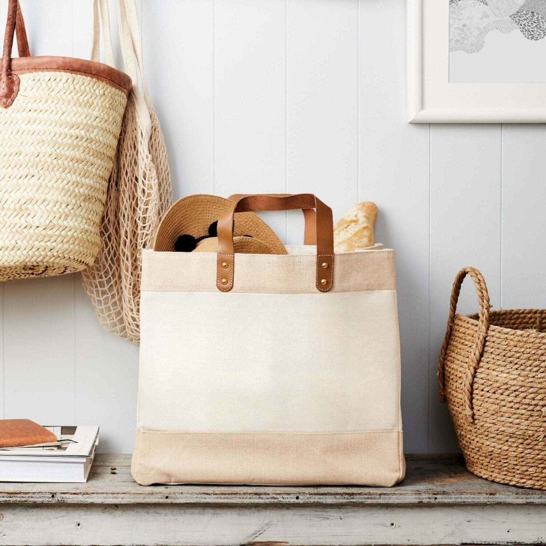 Natural canvas market tote bag with leather handles standing open on wooden floor